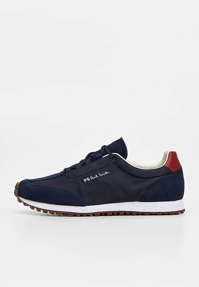 Navyblauer Sneaker mit weißer Sohle, braunem Profil, rotem Fersenlaschen, schwarzen Schnürsenkeln und „PS Paul Smith“-Logo an der Seite.