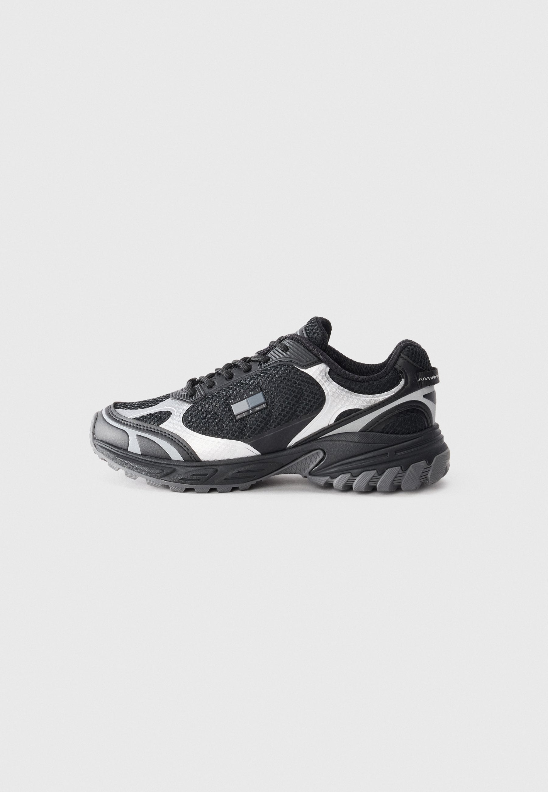 Schwarz-weißes Sportschuh-Modell aus Netz- und Synthetikmaterialien, mit einer strukturierten Sohle, geschwungenem Design und auffälligen Akzenten.