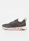 Lässiger grauer Sneaker mit roten Akzenten, weißer Sohle mit runden Ausschnitten, Schnürsenkeln und Zuglaschen an Zunge und Ferse.