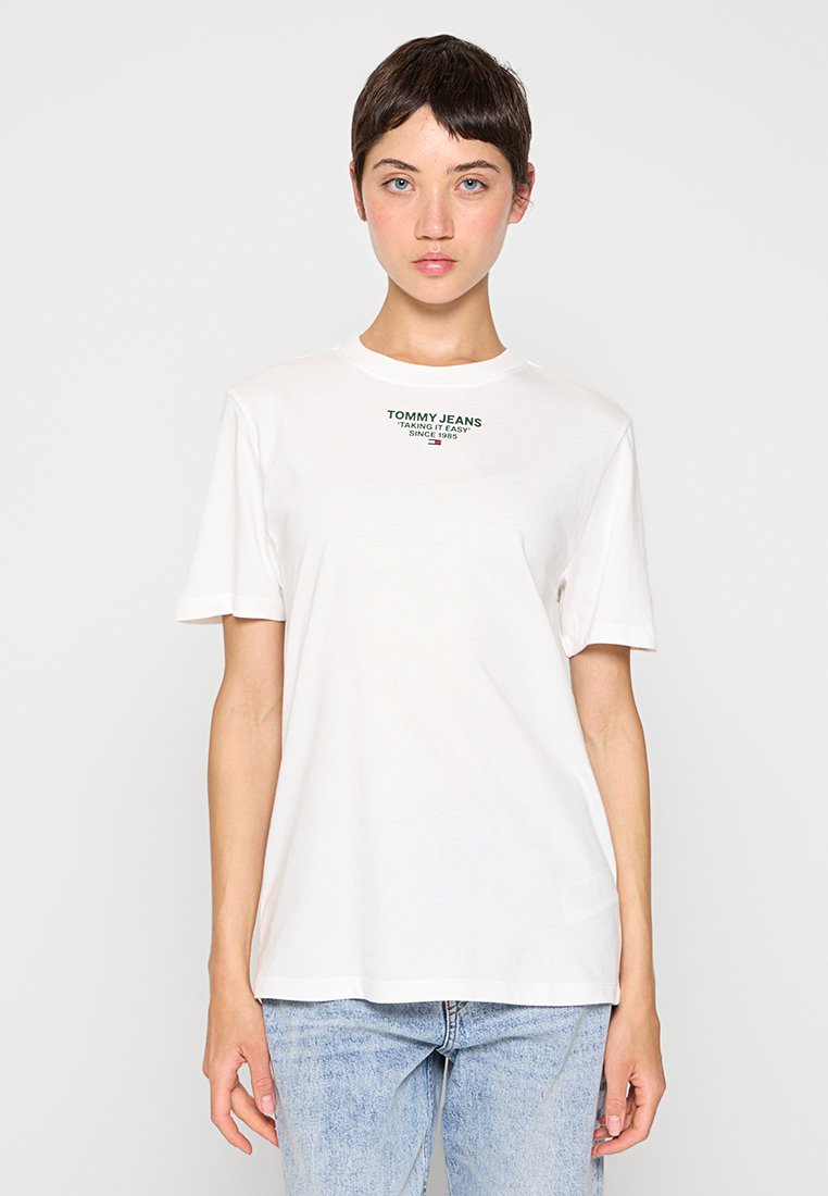 Weißes Baumwoll-T-Shirt mit kurzen Ärmeln, mit grüner "TOMMY JEANS"-Markierung auf der Brust. Gerader Schnitt und weiche Textur.