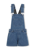 Denimlatzhosen mit verstellbaren Trägern, Fronttasche und kurzen Beinen. Blaue Waschung, silberne Knöpfe und kontrastierende schwarze Trägerakzente.