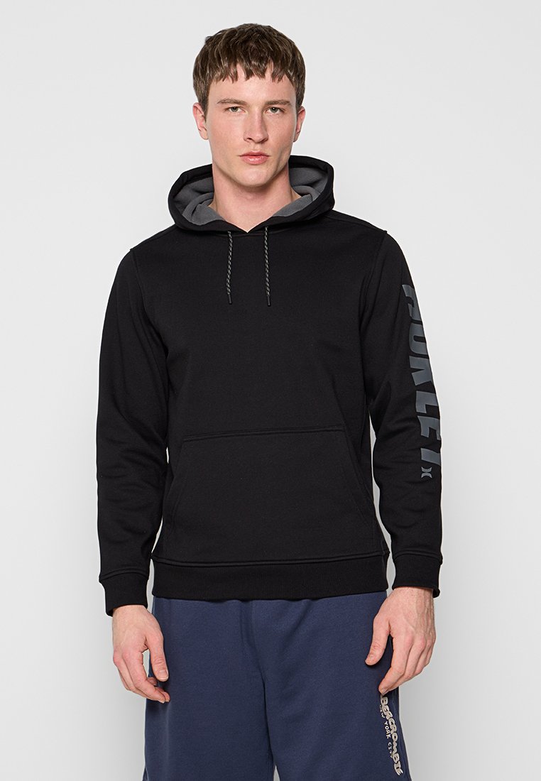 Schwarzer Kapuzenpullover mit grauem Innenfutter. Großes "Hurley"-Logo in Grau auf dem linken Ärmel, Kängurutasche auf der Vorderseite.