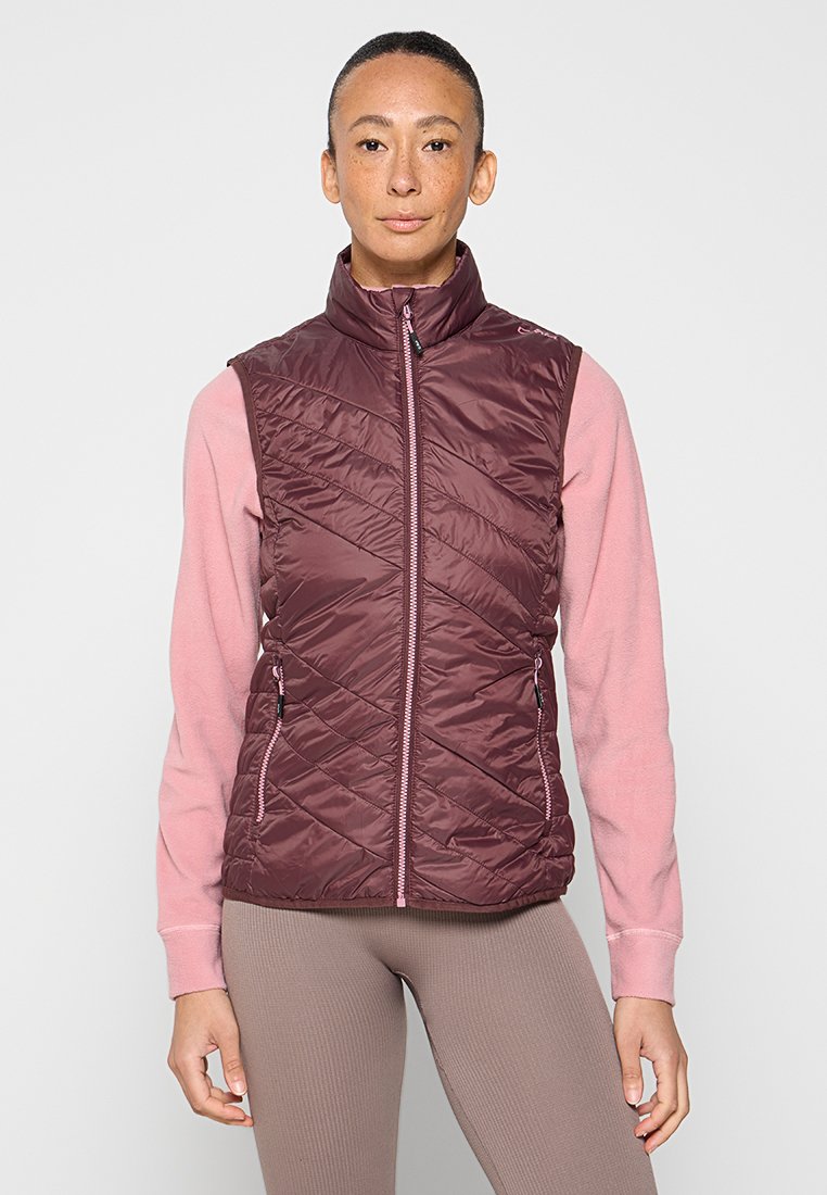 Bordeauxfarbene, gesteppte Weste mit hohem Kragen, Reißverschluss vorne und zwei Seitentaschen. Getragen über einem hellrosa Langarmshirt, was einen schichten Look bietet.