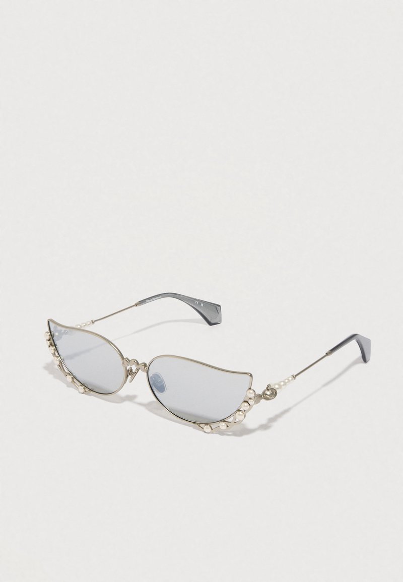 Katzenaugen-Sonnenbrille mit silbernem Rahmen, hellgrauen Gläsern und einer dekorativen Perlenakzent entlang der Oberseite. Schmale Bügel mit einem eleganten Design.