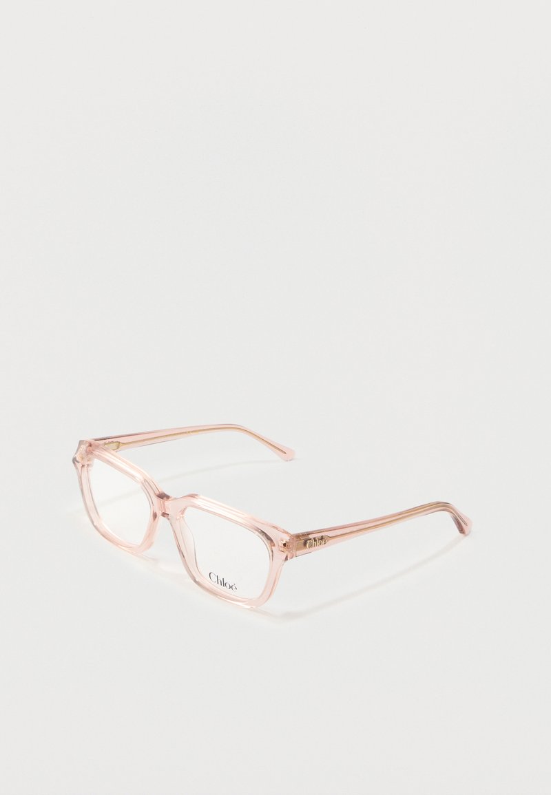 Hellrosa transparente rechteckige Brillengestelle mit klaren Gläsern auf einer weißen Oberfläche liegend.
