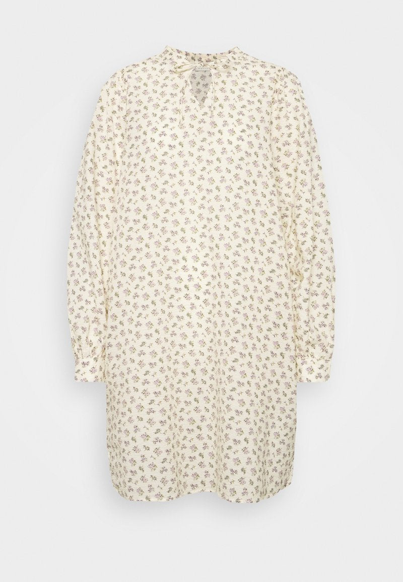 Blumenkleid in Creme mit kleinen lila Blumen, langärmlig, hoher Kragen und Schlitzdetail vorne. Weicher Stoff.