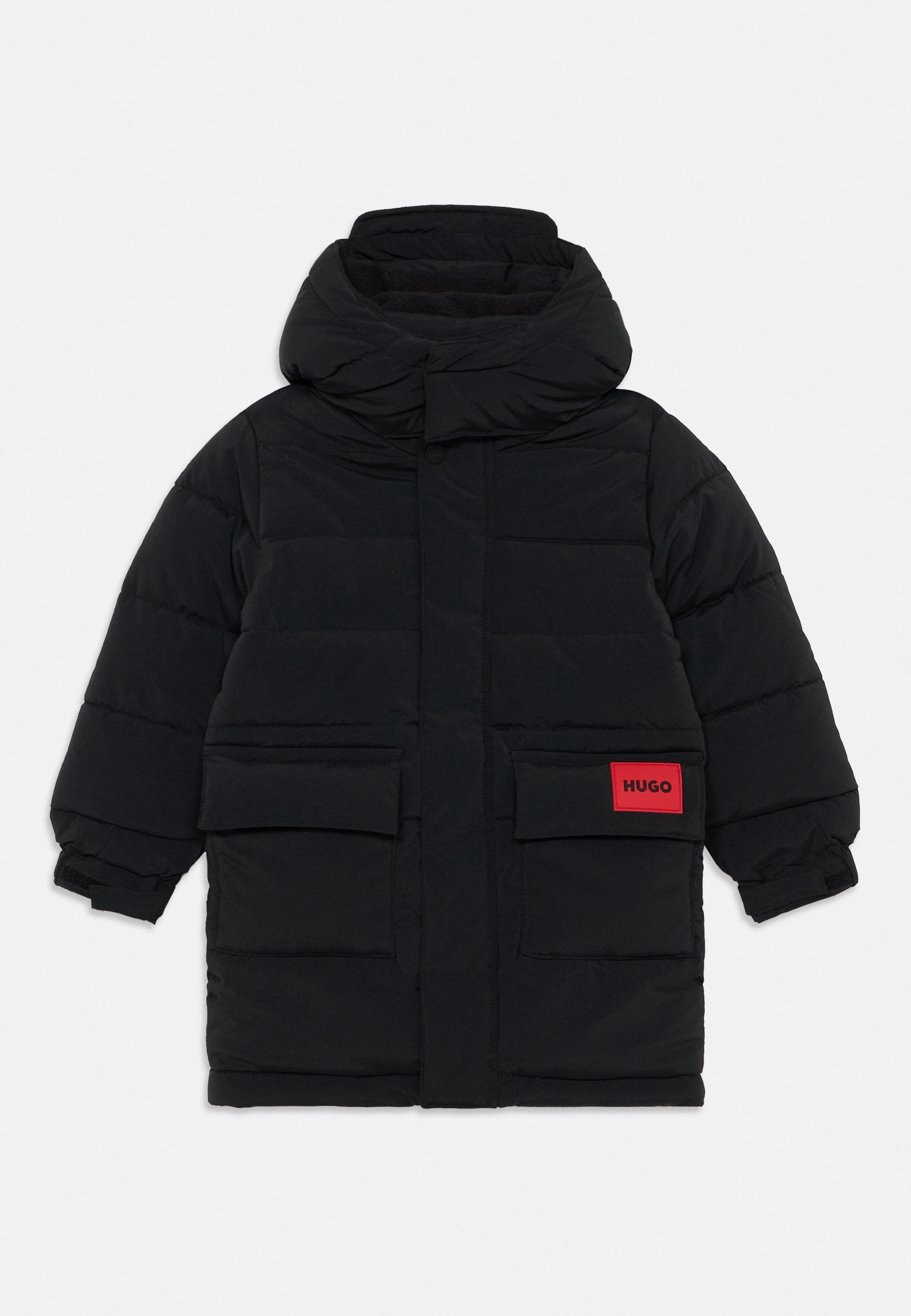 Schwarze Pufferjacke mit hohem Kragen, zwei Fronttaschen und einem leuchtend roten Etikett mit der Aufschrift "HUGO." Strukturiertes, isoliertes Design.