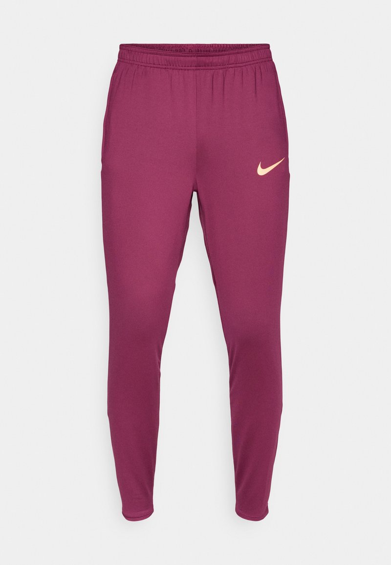 Bordeauxfarbene Sporthose mit schmalem Schnitt, elastischem Bund und kleinem beigen Nike-Logo am linken Oberschenkel. Glattes, dehnbares Material.