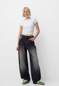 Schwarze weite Jeans mit verwaschenen Details, kombiniert mit einem taillierten weißen Cropped-Top. Enthält einen Knopfverschluss, fünf Taschen und eine lockere Passform.