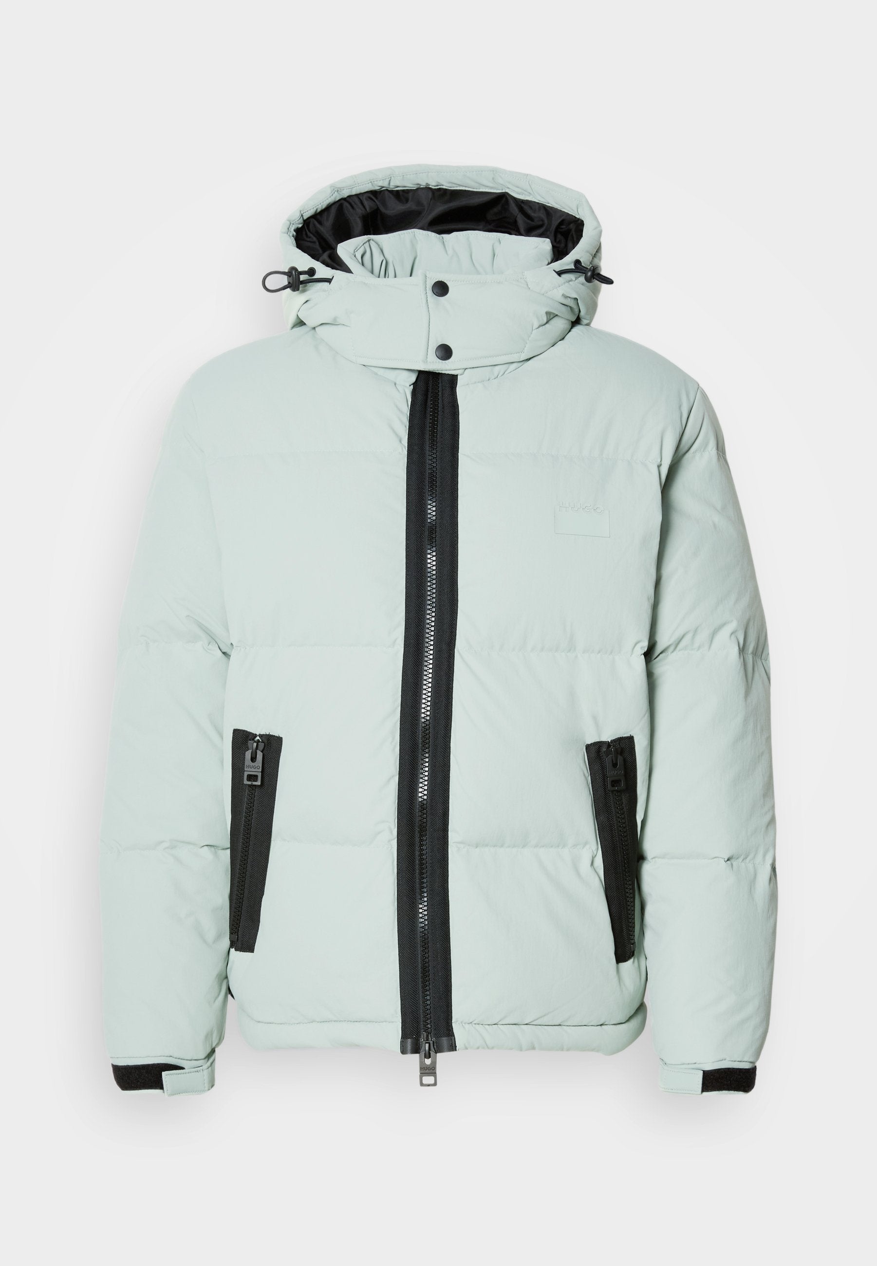 Gepolsterte Jacke in hellem Mintgrün mit hohem Kragen, schwarzem Reißverschluss und zwei Seitentaschen. Besitzt elastische Manschetten und eine minimale Markenkennzeichnung.