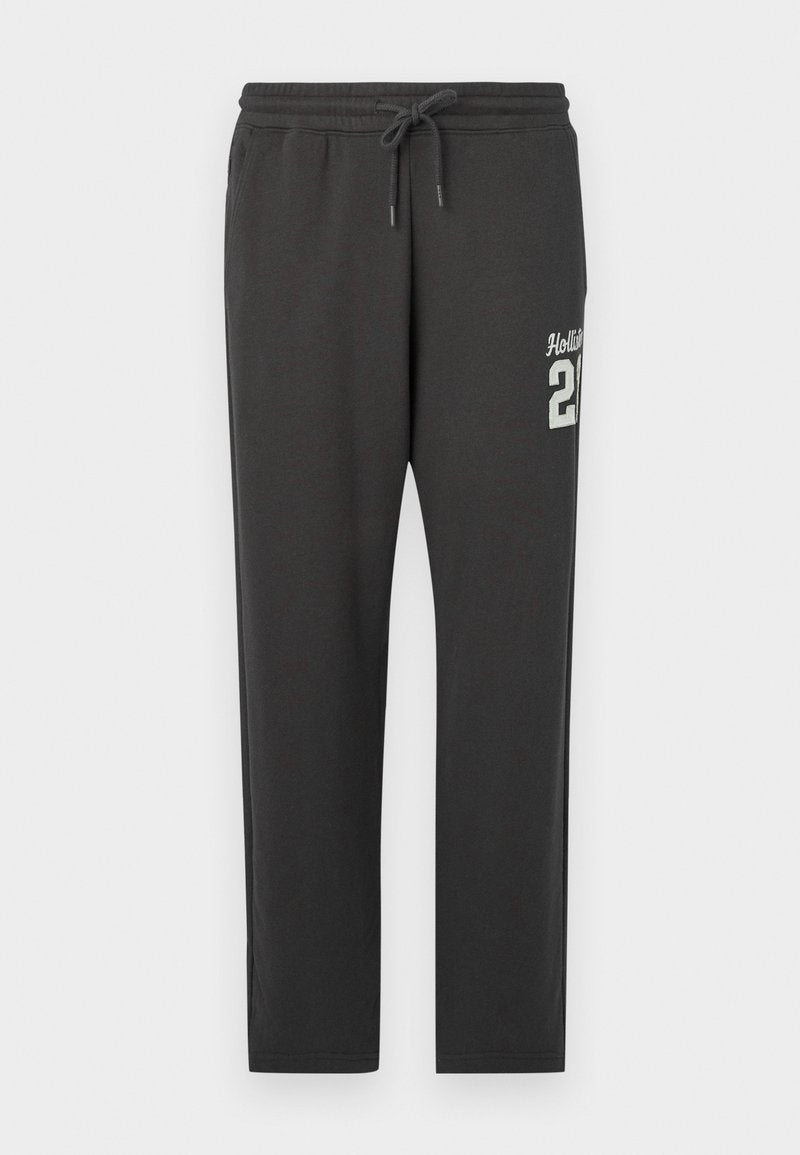 Dunkelgraue Sweatpants mit elastischem Bund und Kordelzug, mit weißem "Hollister 21"-Text auf der oberen linken Oberschenkel.