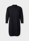 Schwarzes, langärmeliges Hemdkleid mit Kragen, durchgehendem Knopfleistenverschluss, seitlichen Taschen und geknöpften Ärmeln, vor schlichter Hintergrundkulisse präsentiert.