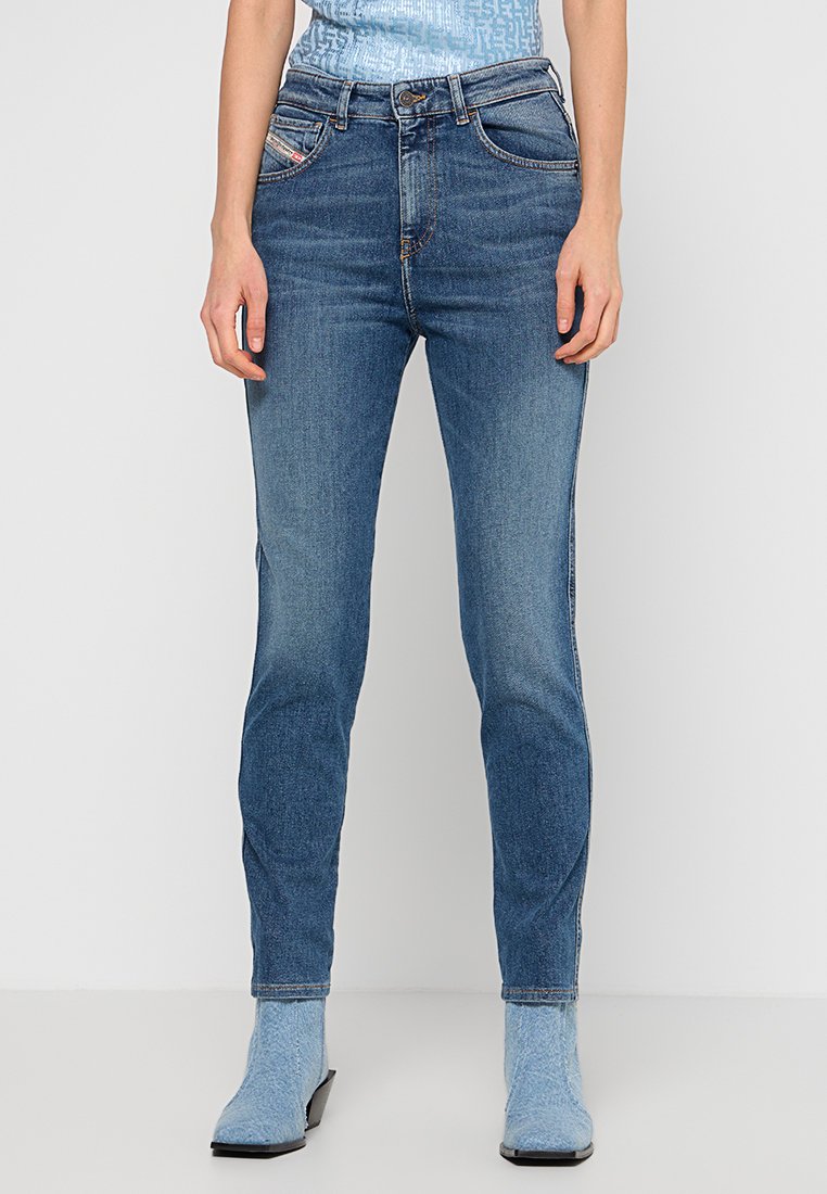 Helle blaue Jeans aus Denim, im Slim-Fit-Schnitt, mit klassischem Fünf-Taschen-Design und subtilen Verbleichungen. Kombiniert mit blauen Stiefeln mit mittelhohem Absatz.