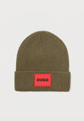 Olivgrüner Strickbeanie mit umgeschlagenem Saum, versehen mit einem roten rechteckigen Etikett mit dem Wort "HUGO" in schwarzer Schrift.
