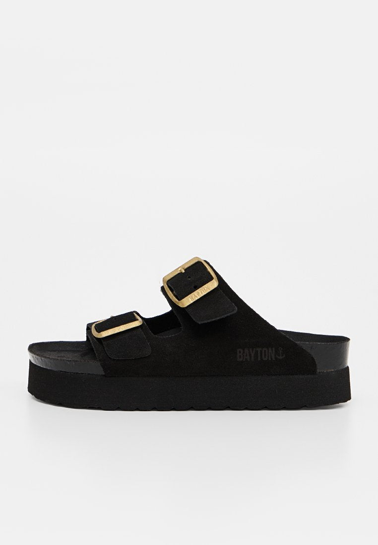 Schwarze Slip-On-Sandale mit zwei verstellbaren Riemen mit goldfarbenen Schnallen und dickem Sohlenprofil.