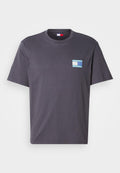 Graues Baumwoll-T-Shirt mit kurzen Ärmeln, versehen mit einem kleinen mehrfarbigen Grafikpatch auf der linken Brust. Klassisches Rundhals-Design.