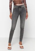 Graue Skinny-Jeans mit verblasster Textur, Fünf-Taschen-Design und Gürtelschlaufen. Begleitet von hellen, Riemchensandalen.