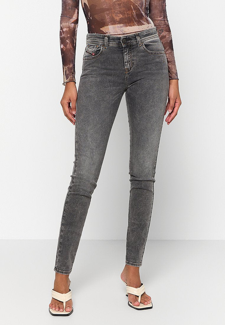 Graue Skinny-Jeans mit verblasster Textur, Fünf-Taschen-Design und Gürtelschlaufen. Begleitet von hellen, Riemchensandalen.