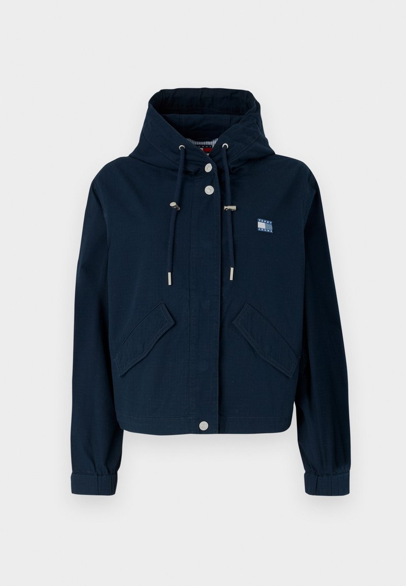 Marineblaues Cropped-Jackett mit einer Kordelzugkapuze, silbernen Beschlägen, zwei Fronttaschen und einem aufgestickten Logo auf der Brust.