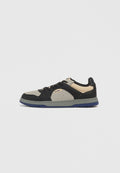 Sneaker mit einem schwarzen Lederobermaterial und grauen Wildledereinsätzen. Merkmale sind Perforationen, schwarze Schnürsenkel, eine Gummisohle und eine blaue Unterseite.