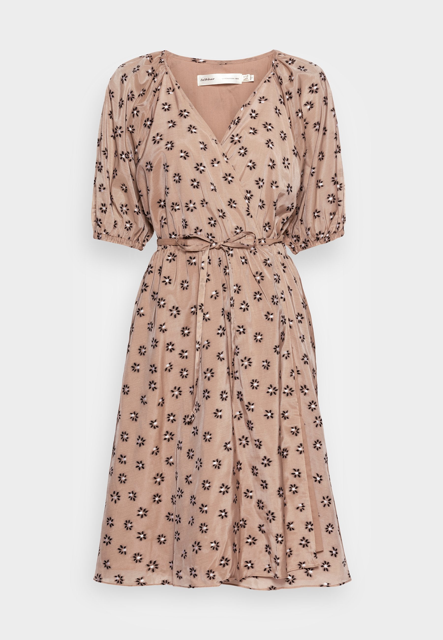 Blumenbedrucktes, knielanges Kleid aus weichem, leichtem Stoff. Mit V-Ausschnitt, Puffärmeln und einem Bindegürtel. Die Farbe ist hellrosa mit schwarzen Blumen.