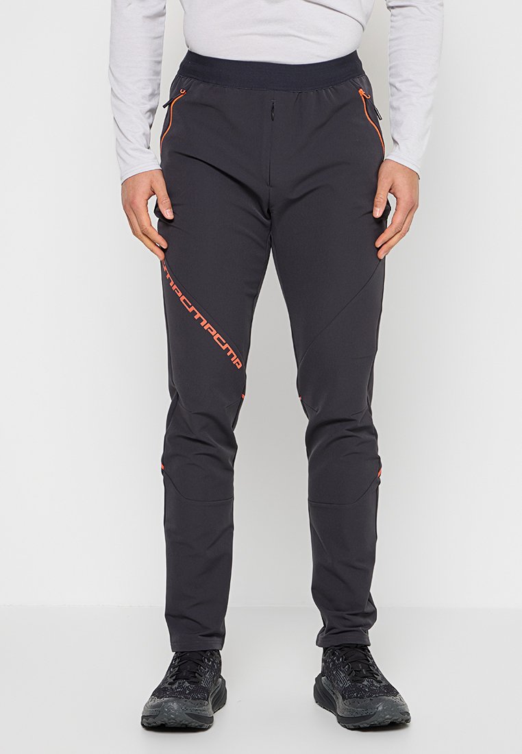 Schwarze Outdoor-Herrenhose aus Softshell-Material, mit orangefarbenen Akzenten, einer Reißverschlusstasche und Knieeinsätzen für Beweglichkeit.