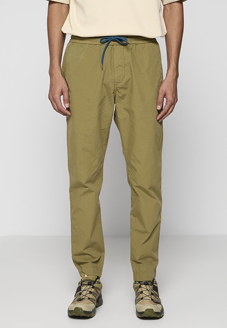 Khaki leichte Hose mit elastischem Bund, blauer Kordel und schmaler geschnittenen Beinen, kombiniert mit beigen Schuhen für einen Outdoor-Look.