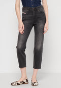 Hoch taillierte schwarze Denim-Jeans mit geradem Schnitt, ausgestattet mit frontalen Taschen und subtilen Waschungen. Kombiniert mit Schuhen im Kuhfell-Muster.