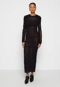 Schwarzes langes Strickkleid mit strukturiertem, durchsichtigen Design, gerader Silhouette und Rundhalsausschnitt. Getragen mit schwarzen spitzen Schuhen.