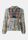 Langärmlige Bluse mit einem komplexen floralen Muster in Blau, Orange und Creme, mit einer gerafften Taille und dekorativen Quasten.