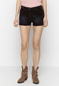 Frau in dunkelbraunen Samtshorts, pinkem gestricktem ärmellosem Top und braunen Wildleder-Stiefeletten, die vor einem weißen Hintergrund steht.