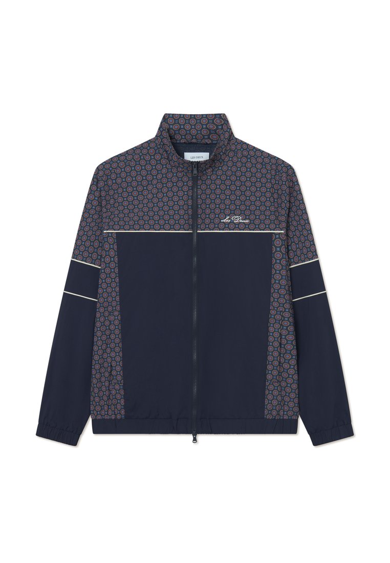 Marinejacke mit einem gemusterten oberen Teil in roten und blauen Kreisen, mit Reißverschluss, Stehkragen und elastischen Bündchen. Verfügt über weiße Akzentstreifen.