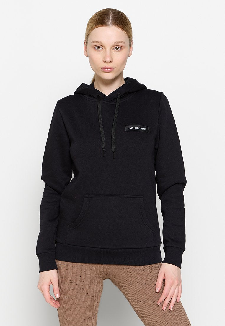 Schwarzer Kapuzenpullover aus weichem Stoff, mit einer Fronttasche, Kordelzug an der Kapuze und einem kleinen Logo-Patch auf der Brust. Lange Ärmel, lockere Passform.
