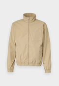 Beige leichte Jacke mit hohem Kragen, Reißverschluss, elastischen Bündchen und Saum, mit kleinem Logo auf der linken Brust. Glatte Textur.