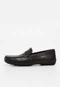 Schwarzer Leder-Slipper mit genähtem Obermaterial und strukturierter Gummisohle, seitlich auf weißem Hintergrund gezeigt.