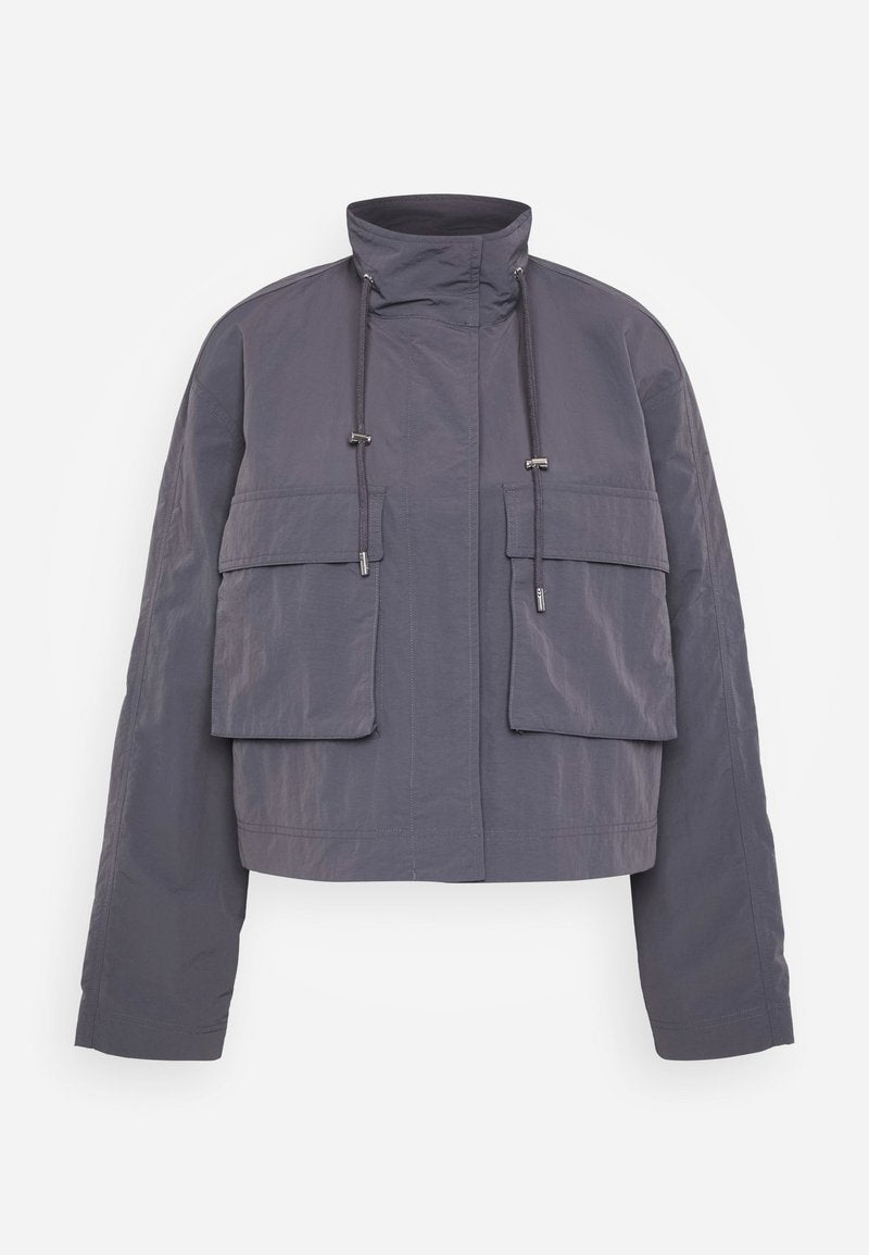 Abgeschnittene Jacke aus grauem Stoff, mit zwei vorderen Taschen, einem hohen Kragen und Kordeln zur Anpassung. Glatte Textur und lässige Passform.
