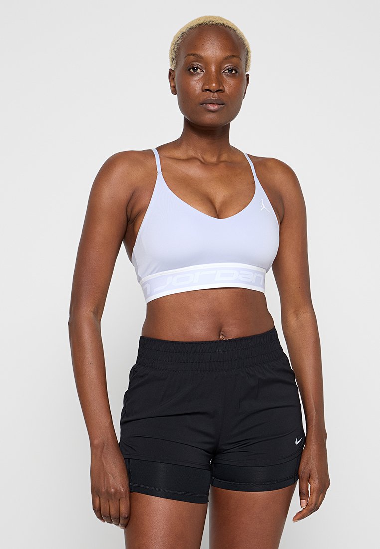 Hellviolettes Sport-BH mit V-Ausschnitt und weißem Markband. Schwarze Sportshorts mit elastischem Bund und dezentem Nike-Logo.