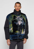Mann trägt schwarze Jacke mit großem, farbenfrohem Wolfsgrafik auf der Vorderseite, steht vor einem schlichten hellgrauen Hintergrund.