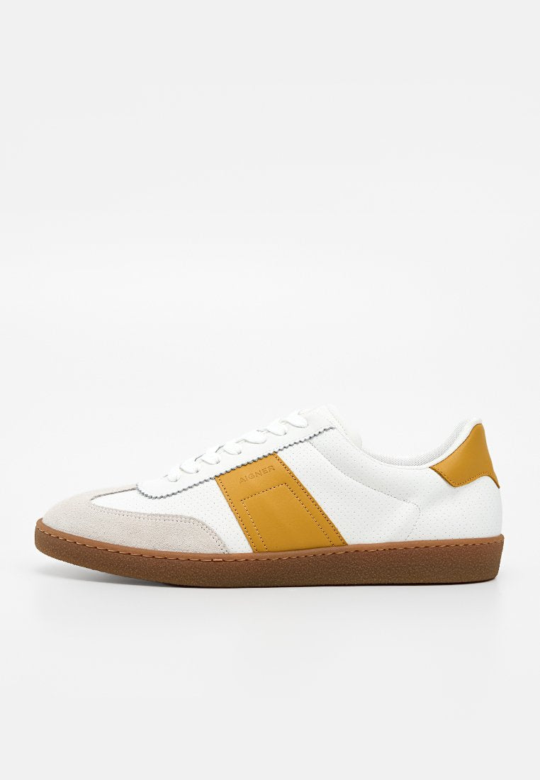 Weißer Sneaker mit brauner Sohle, beiger Wildlederkappe und senfgelben Lederakzenten an Seite und Ferse.