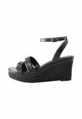 Schwarze Wedgesandalen mit einer geflochtenen Jute-Plattform, ausgestattet mit überkreuzten strukturierten Riemen und einem verstellbaren Knöchelriemen. Flacher Absatz.