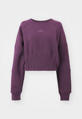 Gekürzter lila Sweatshirt mit langen Raglanärmeln, gerippten Bündchen und einem dezenten Logo auf der Vorderseite. Glatte Textur mit einem lässigen Schnitt.