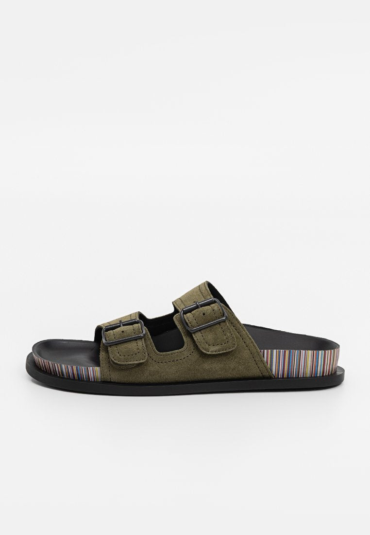 Grüne Wildledersandalen mit zwei verstellbaren Schnallen, einem schwarzen Fußbett und einer gestreiften, mehrfarbigen Sohle. Offene Zehenpartie für einfaches Anziehen.