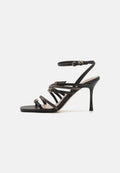 Schwarze High-Heelsandalen verfügen über mehrere schlanke Riemen, eine quadratische Zehenpartie und metallische Akzente auf der Vorderseite. Mit verstellbarem Knöchelriemchen.