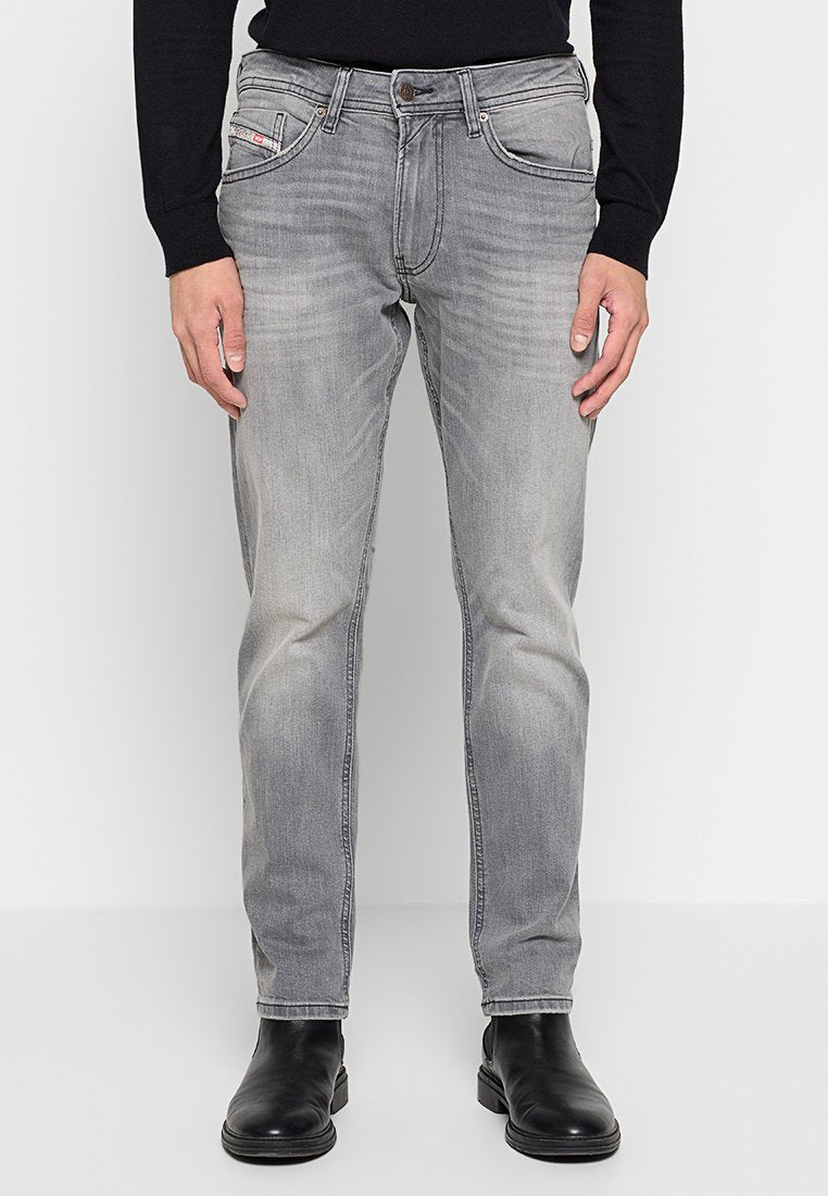 Graue Denim-Jeans mit Slim-Fit, ausgestattet mit Vordertaschen, flachen Nieten und leichter Ausbleichung. Getragen mit schwarzen Ankle-Boots.