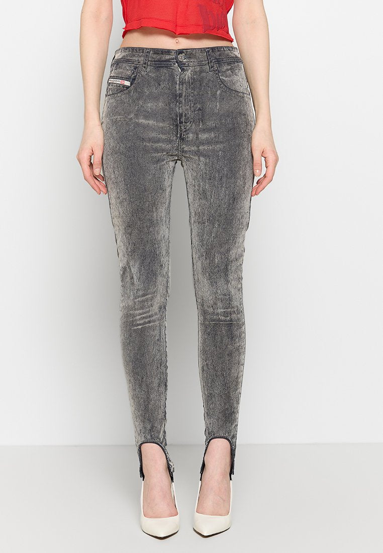 Frau trägt hochtaillierte, acid-wash Skinny Jeans mit Vorderrepuestos und Reißverschlüssen an den Knöcheln, kombiniert mit weißen spitzen Absätzen.