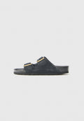 Schwarze Wildleder-Sandalen mit zwei verstellbaren Riemen, goldenen Schnallen und strukturierten Sohlen, die ein dezentes Logo an der Seite aufweisen.