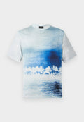 Kurzärmeliges T-Shirt mit blau-weißem Farbverlauf, der eine Strandszene mit Palmen und Wasserreflexionen zeigt.