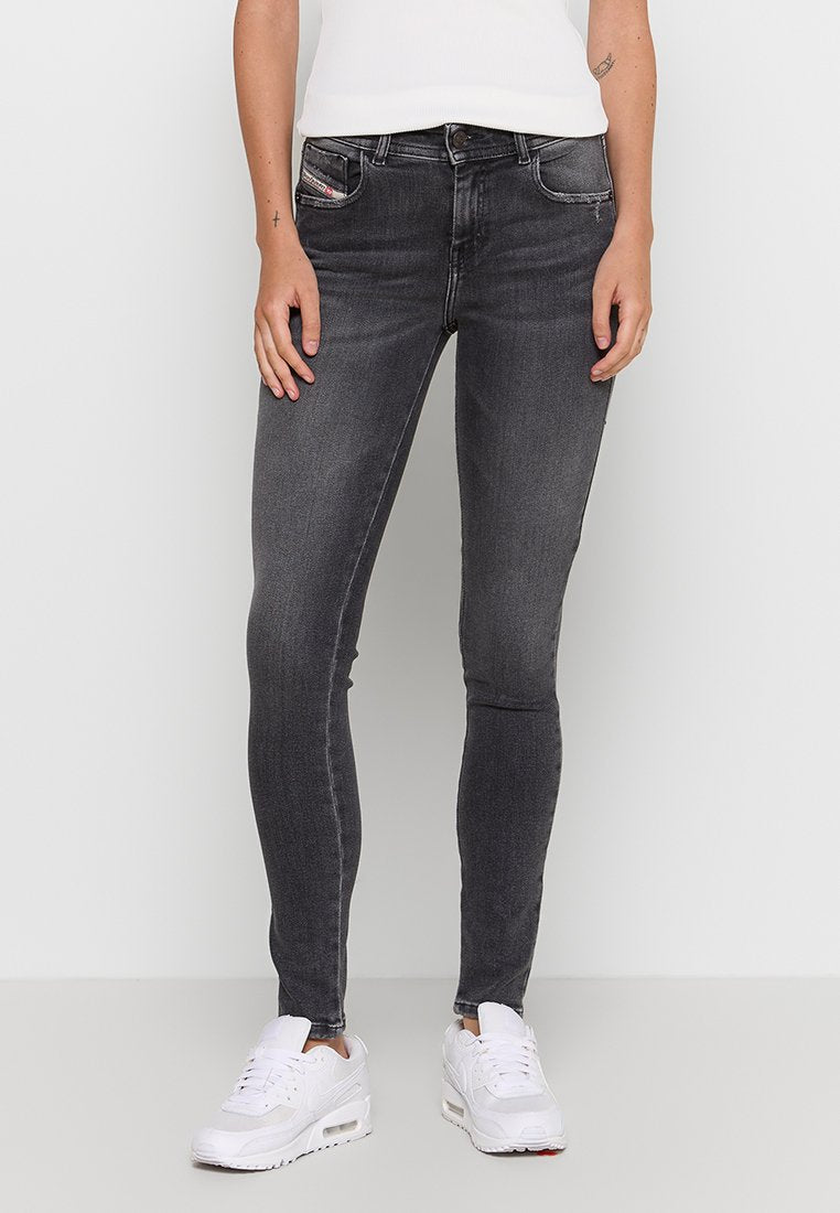 Schmale Jeans aus dunkelgrauem Denim mit subtilen Verwaschungen, Fünf-Taschen-Design und kontrastierenden Nähten. Kombiniert mit weißen Sportschuhen.