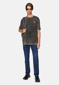 Abgewetztes graues T-Shirt mit Rundhalsausschnitt und rotem Logo, kombiniert mit dunkelblauen Jeans und schwarzen Sneakers. Sonnenbrille und Schultertasche inklusive.