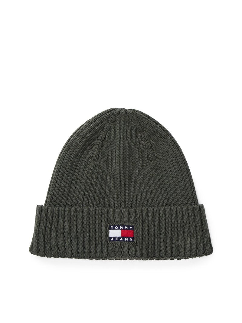 Grüne Strickmütze mit geripptem Bund, ausgestattet mit einem kleinen Patch mit dem "TOMMY JEANS"-Logo in Rot, Weiß und Blau.
